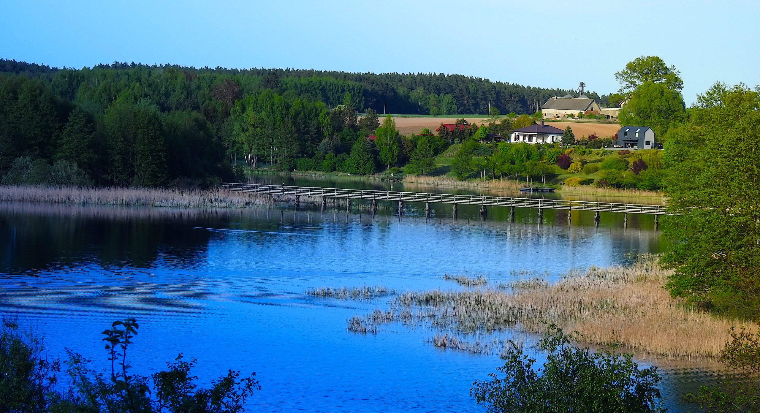 Lärchenholzbrücke auf dem Jakobsweg und Kirche am See